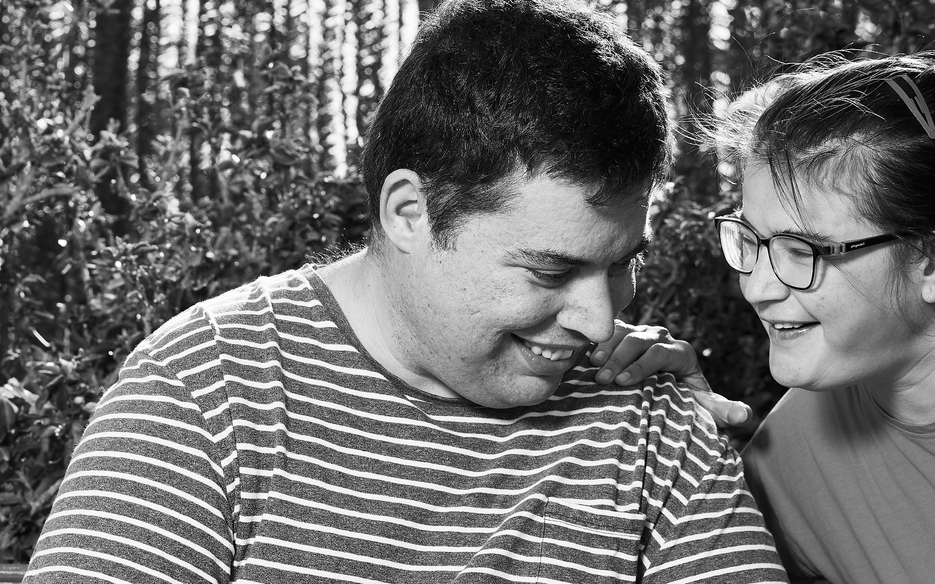 Dos personas con autismo comparten un momento de complicidad mientras sonríen.