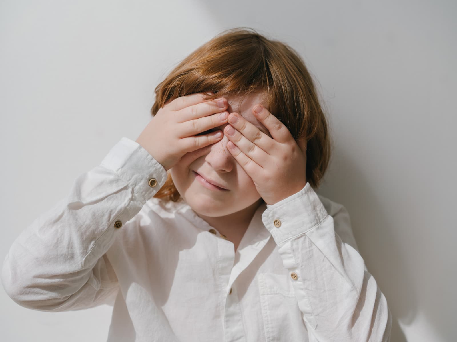 Un niño con autismo se tapa los ojos con sus manos.