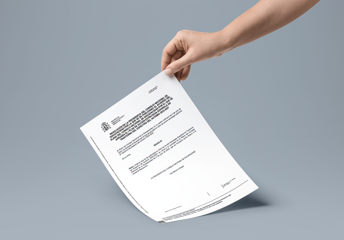 Una mano de mujer sujeta el documento de la resolución de la presidencia del consejo nacional de discapacidad por la que se da publicidad al acuerdo del pleno del consejo nacional de discapacidad por el que se aprueba el plan de acción estrategia española en trastornos del espectro del autismo 2023-2027