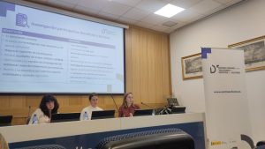 Fotografía en la que se ve a las representantes del Centro Español de Autismo dando una charla formativa. Detrás de ellas una pantalla con la presentación de la formación.