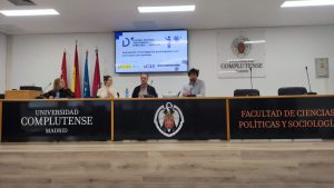 Fotografía de las ponentes en la formación sobre investigación participativa ofrecida por el Centro Español de Autismo en la Facultad de Ciencias Políticas y Sociología de la Universidad Complutense de Madrid. Los y las intervinientes están sentados en una mesa que tiene una gran pantalla detrás con la presentación del seminario.