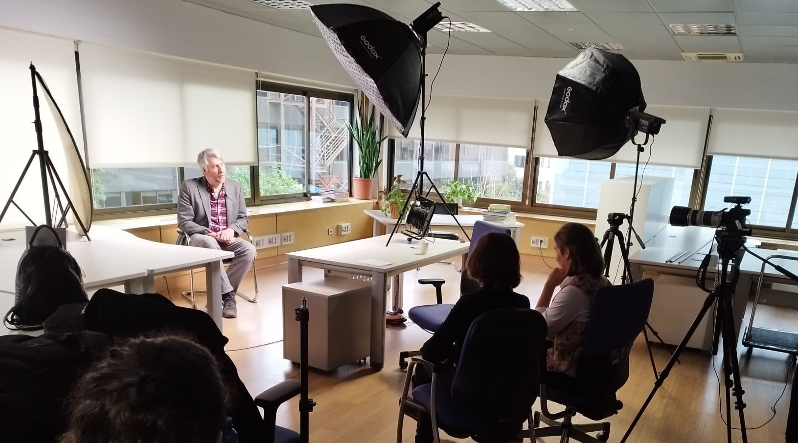 Fotografía en la que se ve al divulgador autista, Pete Wharmby bajo los focos de un set de grabación. Alrededor las personas que entrevistan y graban la entrevista de espaldas.