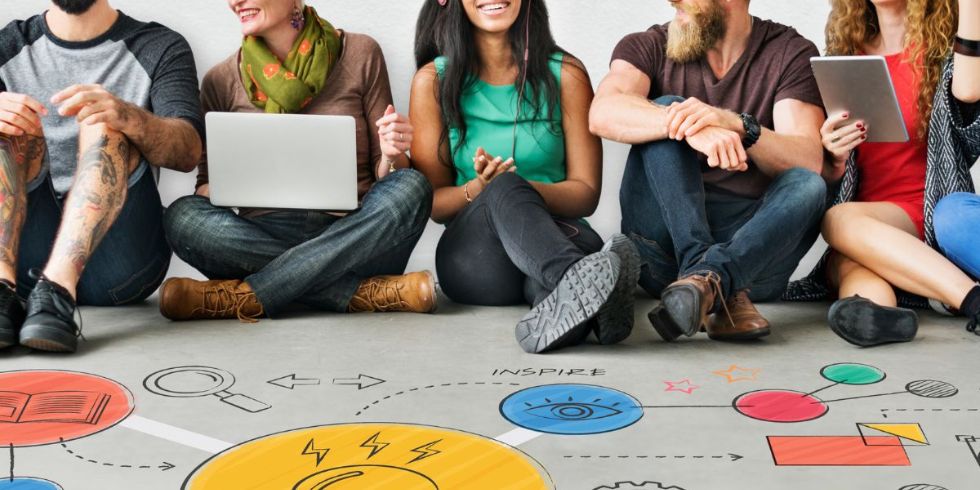 Un grupo de personas comparte datos sobre investigación participativa en autismo, sobre un suelo en el que están dibujados iconos de colores.