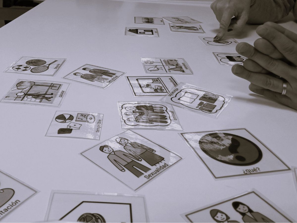 Un par de personas con autismo escogen pictogramas de comunicación para identificar los temas que les parecen más importantes para investigar sobre autismo.