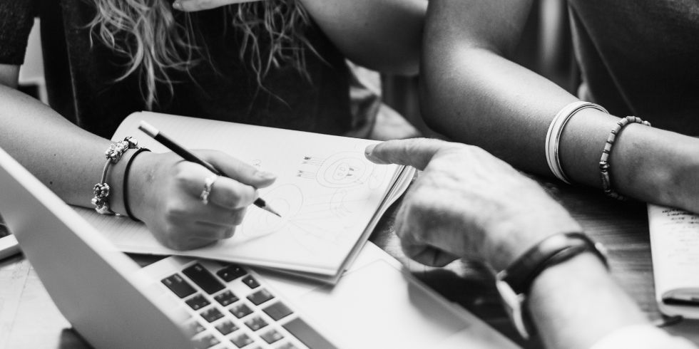 Dos personas comparten conocimientos sobre autismo entorno a una libreta y un ordenador.