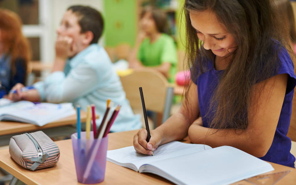 Una niña escribe con lápices de colores